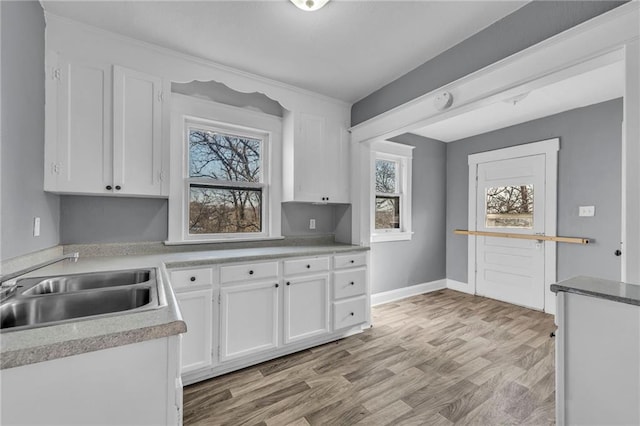 kitchen with plenty of natural light, white cabinets, and light wood-style flooring