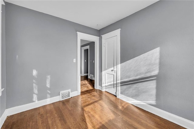 unfurnished room featuring visible vents, baseboards, and wood finished floors