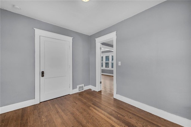 unfurnished room featuring visible vents, baseboards, and dark wood finished floors