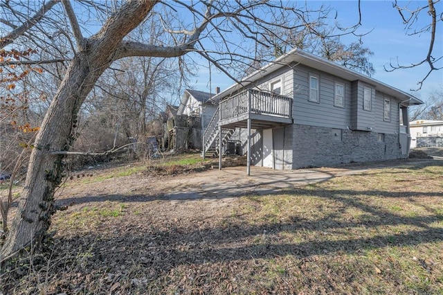 view of side of property with a deck, stairway, a lawn, and driveway