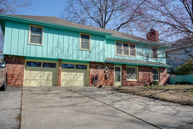 view of front of house featuring brick siding, driveway, a chimney, and a garage