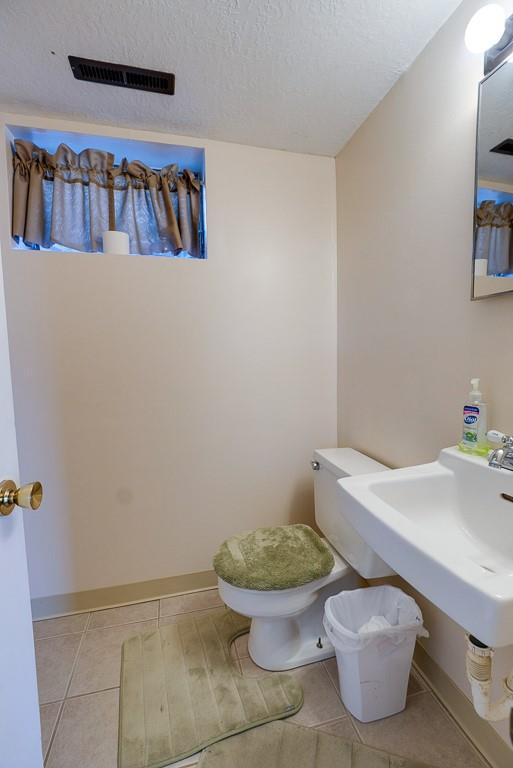 bathroom featuring baseboards, visible vents, tile patterned flooring, a textured ceiling, and toilet