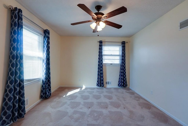 empty room with visible vents, carpet floors, baseboards, and ceiling fan