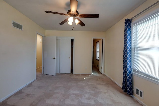 unfurnished bedroom with baseboards, visible vents, light carpet, and a closet