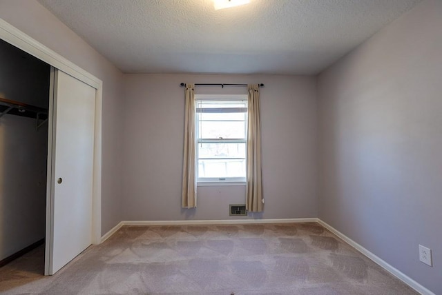 unfurnished bedroom featuring baseboards, carpet floors, a textured ceiling, and a closet