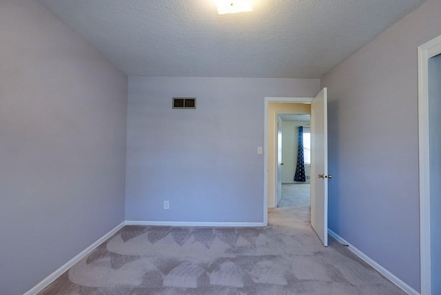 unfurnished room with carpet flooring, baseboards, visible vents, and a textured ceiling