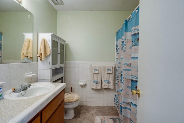 bathroom featuring a wainscoted wall, visible vents, toilet, tile walls, and vanity