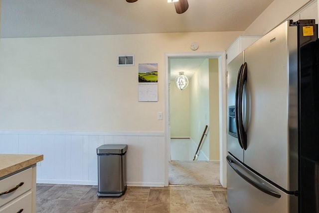 kitchen with visible vents, stainless steel fridge with ice dispenser, light countertops, wainscoting, and white cabinetry