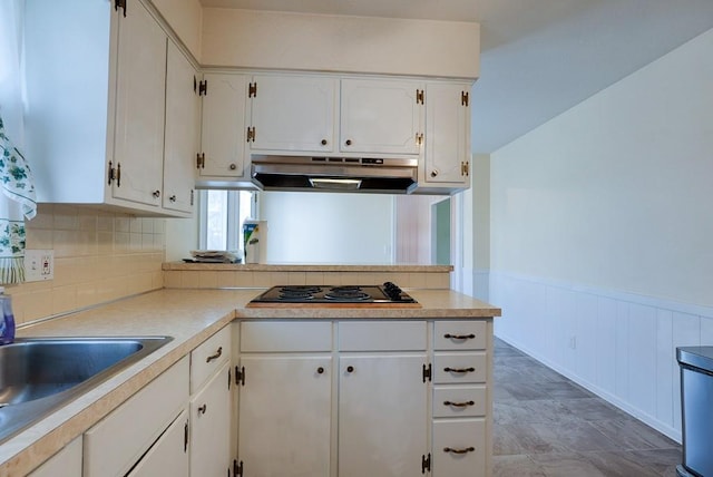 kitchen featuring under cabinet range hood, white cabinets, wainscoting, light countertops, and black electric cooktop