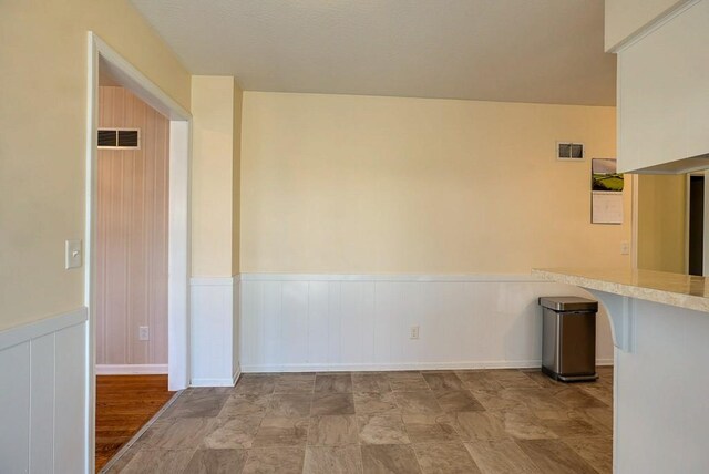 empty room with visible vents and wainscoting