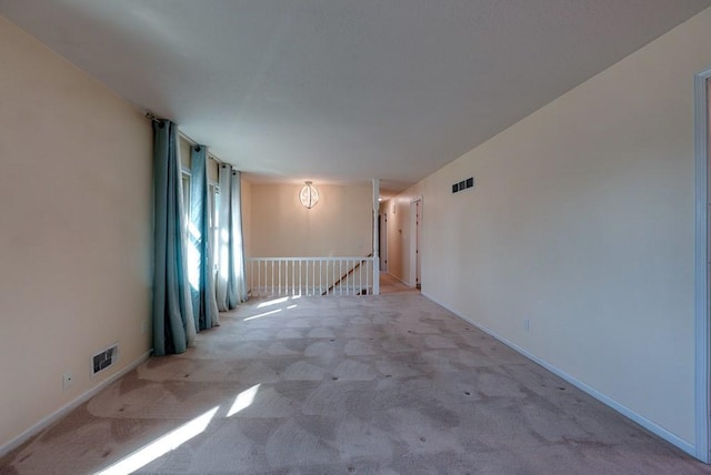 empty room featuring carpet, visible vents, and baseboards