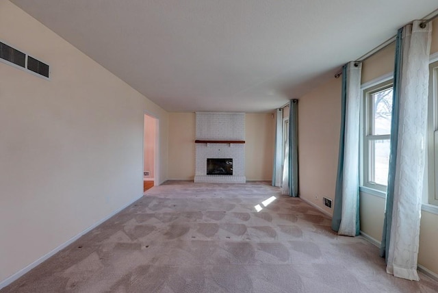 unfurnished living room with visible vents, light carpet, baseboards, and a fireplace