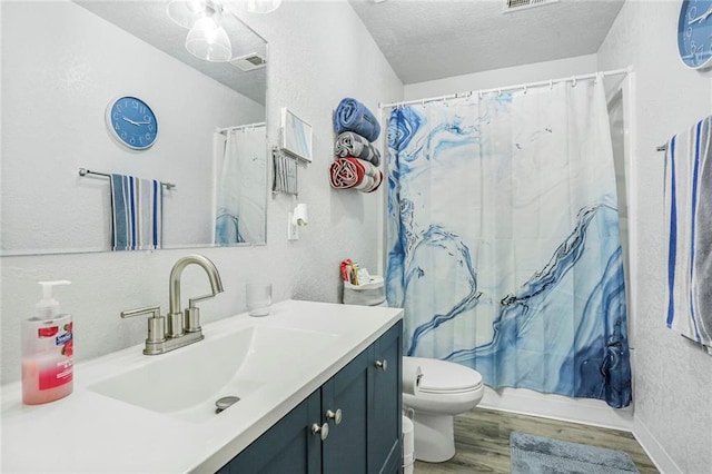 bathroom featuring a textured wall, a textured ceiling, wood finished floors, and toilet