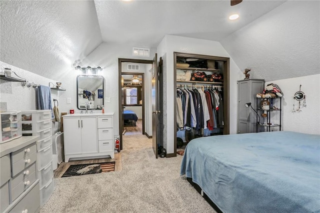 bedroom with a closet, visible vents, a textured ceiling, and lofted ceiling