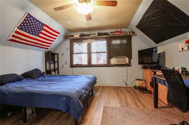 bedroom featuring ceiling fan, lofted ceiling, a textured ceiling, and wood finished floors