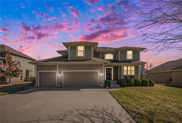 prairie-style house with stucco siding, a lawn, concrete driveway, and an attached garage