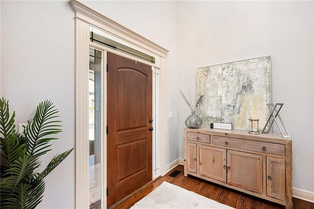 foyer entrance with dark wood-type flooring and baseboards