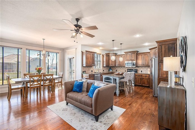 living room featuring recessed lighting, a textured ceiling, dark wood finished floors, and ceiling fan with notable chandelier