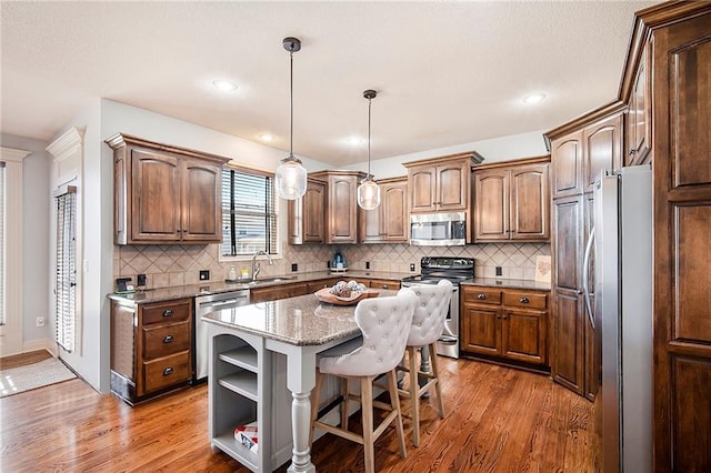 kitchen featuring a sink, open shelves, appliances with stainless steel finishes, and wood finished floors