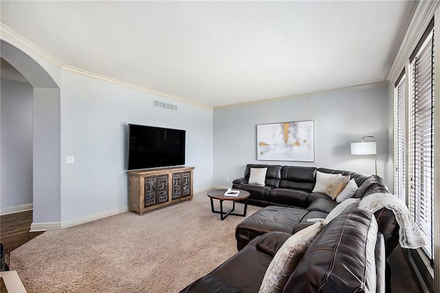 carpeted living room featuring visible vents, arched walkways, baseboards, and crown molding