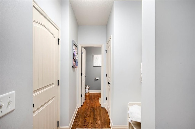 corridor featuring baseboards and wood finished floors