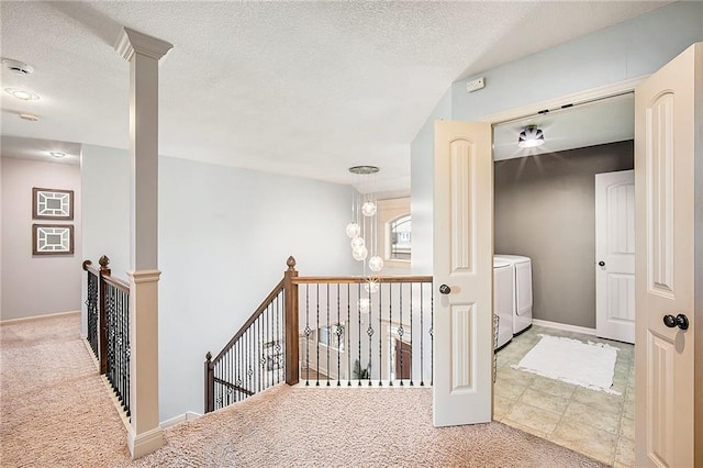 hallway featuring an upstairs landing, washing machine and dryer, a textured ceiling, and carpet floors