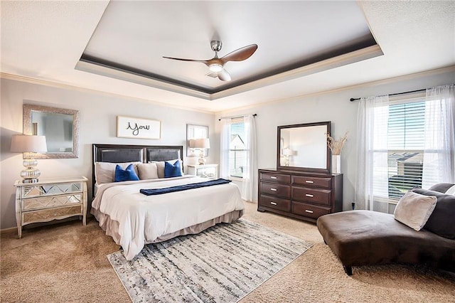 bedroom with a tray ceiling, ornamental molding, a ceiling fan, and light carpet