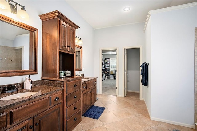 full bath featuring baseboards, double vanity, a sink, tile patterned flooring, and a spacious closet