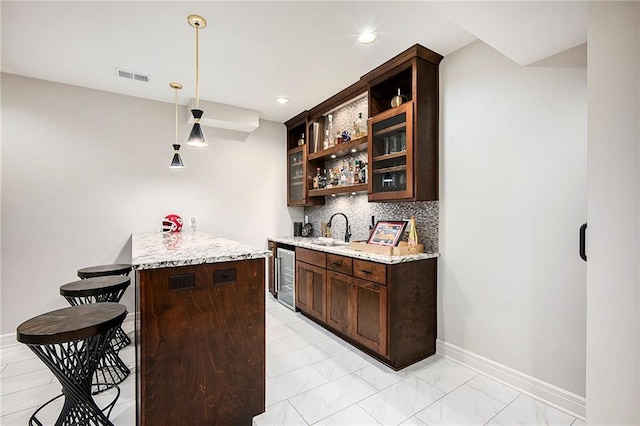 bar with visible vents, a sink, backsplash, wine cooler, and baseboards