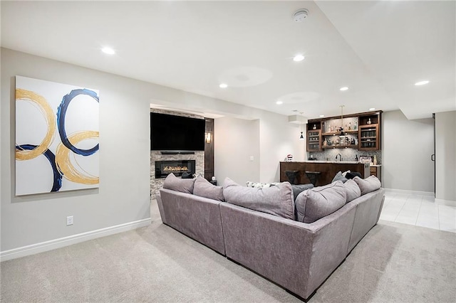 living room featuring light carpet, a stone fireplace, recessed lighting, and indoor wet bar