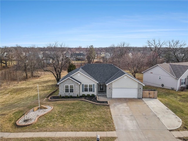 view of front of property featuring a garage, driveway, a front yard, and roof with shingles