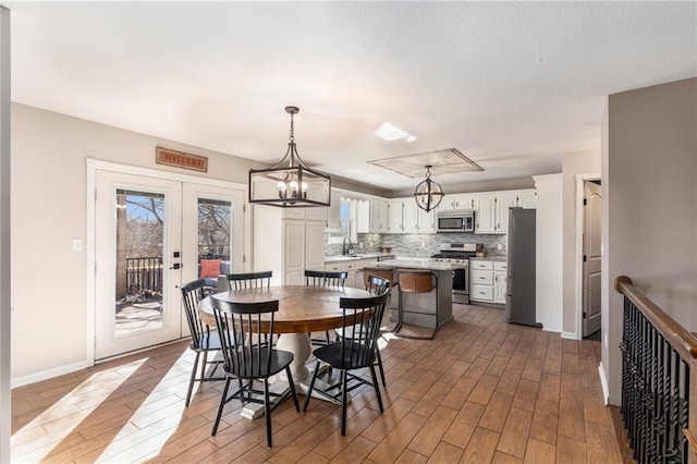 dining area featuring french doors, baseboards, wood finished floors, and a chandelier