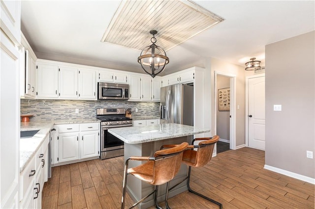 kitchen with decorative backsplash, wood finished floors, appliances with stainless steel finishes, and a kitchen island