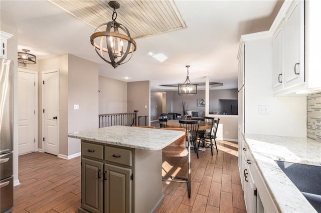 kitchen featuring an inviting chandelier, wood finished floors, backsplash, and a center island