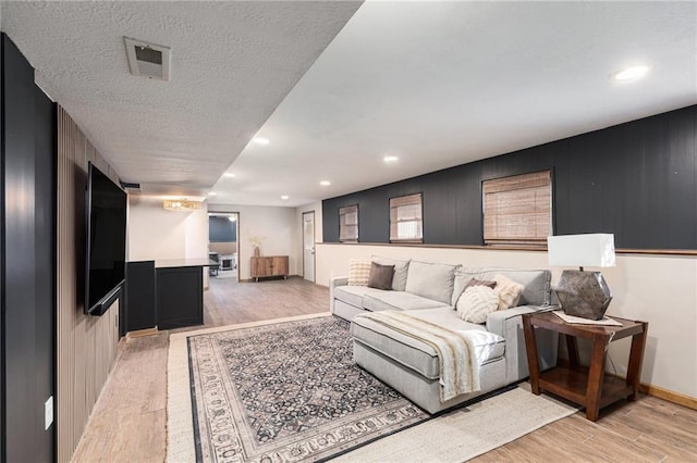 living room with recessed lighting, visible vents, a textured ceiling, and light wood finished floors