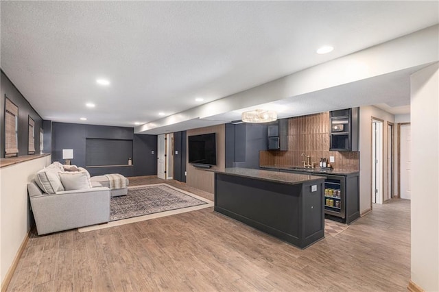 living room with baseboards, light wood-style flooring, recessed lighting, indoor wet bar, and wine cooler