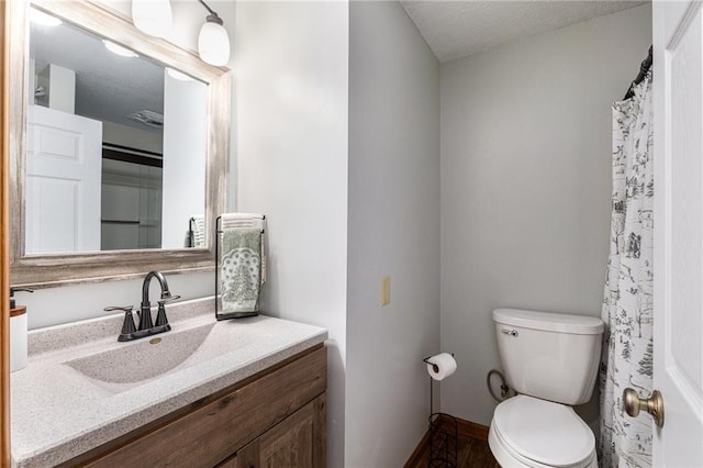 full bath with baseboards, toilet, vanity, and a textured ceiling