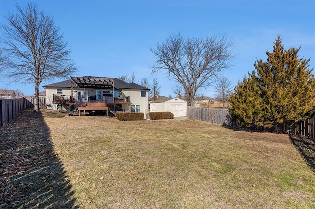 view of yard featuring a deck, an outbuilding, a fenced backyard, and a shed