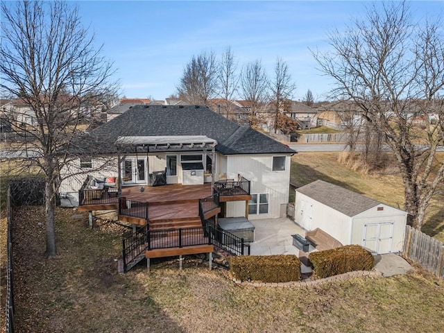 back of house with fence, a shed, roof with shingles, an outdoor structure, and a deck