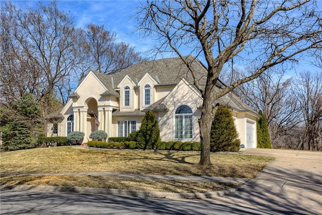 view of front facade featuring concrete driveway, an attached garage, a front yard, and stucco siding