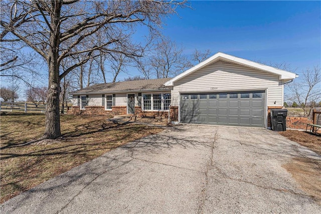 ranch-style house with aphalt driveway, a garage, fence, and brick siding