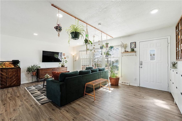 living room with recessed lighting, wood finished floors, baseboards, and a textured ceiling