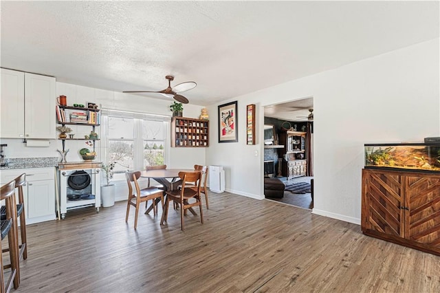 dining area with a textured ceiling, wood finished floors, and a ceiling fan