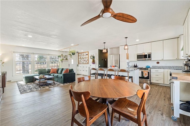 dining space with a textured ceiling, recessed lighting, light wood finished floors, and ceiling fan