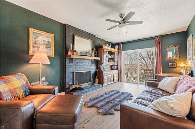 living area with ceiling fan, a textured ceiling, wood finished floors, and a fireplace