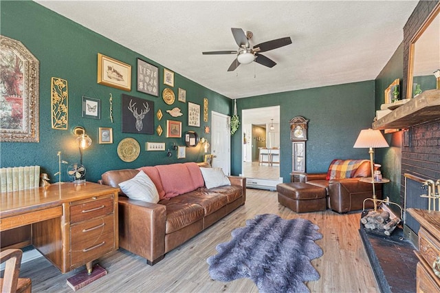 living room featuring a fireplace, a textured ceiling, ceiling fan, and wood finished floors