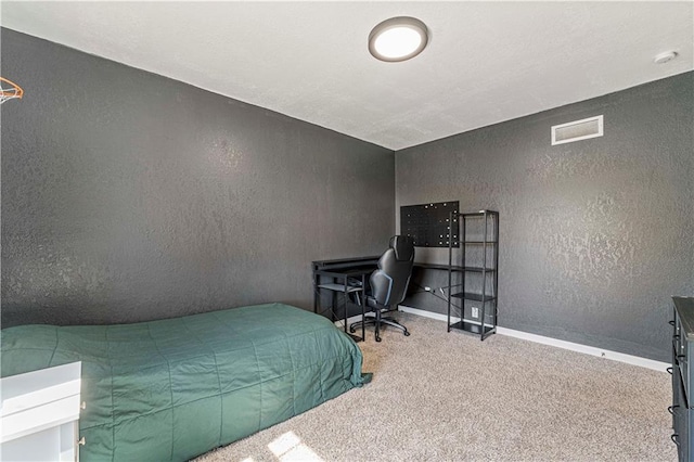 bedroom with carpet, a textured wall, visible vents, and baseboards