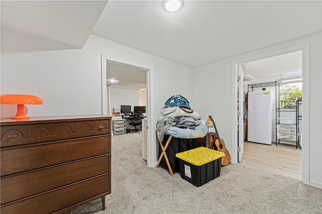 carpeted bedroom with freestanding refrigerator