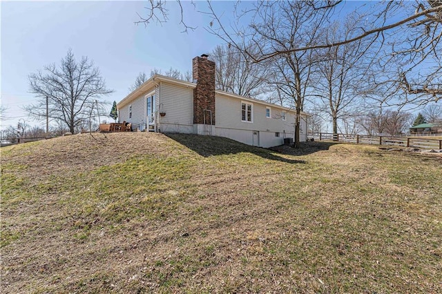 view of home's exterior with a yard, fence, and a chimney