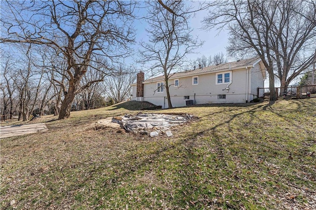 back of property featuring a lawn, cooling unit, and a chimney